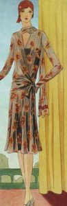 1920's fashion. Ruth Wade. Rust dress and hat beside yellow curtain w
